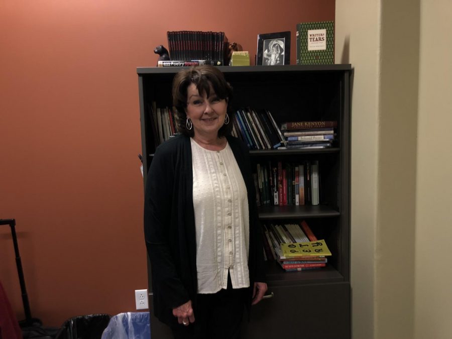 English Professor, Rachael Stewart, poses in front of the many bookshelves in her office.
