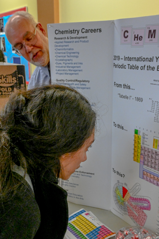 ECC student examine the periodic table as chemistry instructor looks on during the hallway STEM fair. The STEM fair is another opportunity to learn outside of the classroom.