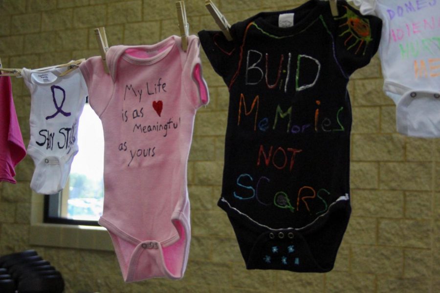 Baby clothes with messages about domestic violence awareness on them.