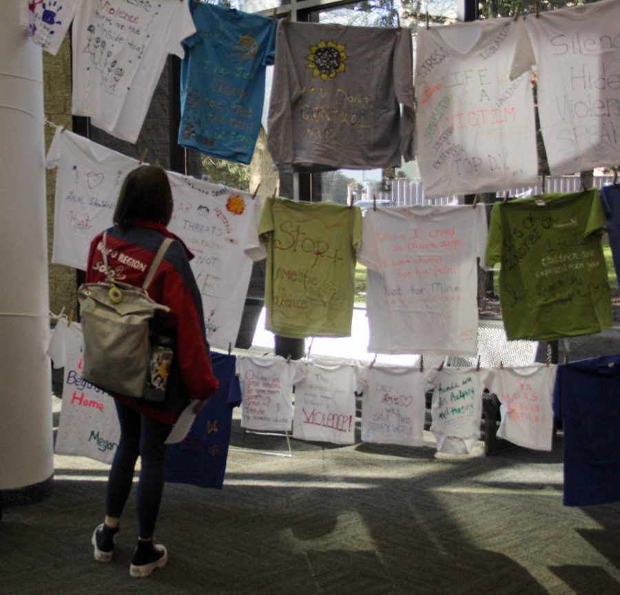 A student looks at the clothesline project for Domestic Violence Awareness Month.