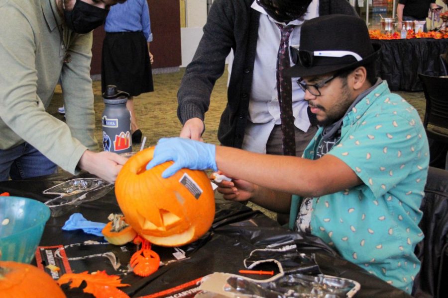 Students work together to carve a pumpkin for the pumpkin carving contest at ECCs Fall Fest.