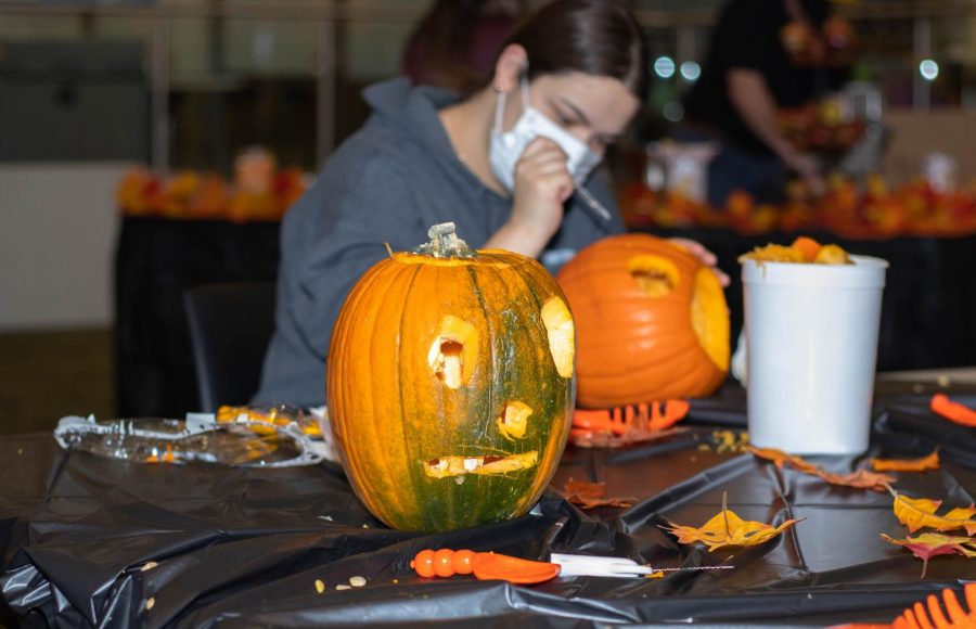 Jack OLantern awaits to be judged while student carves a pumpkin in the background on Oct. 27. 