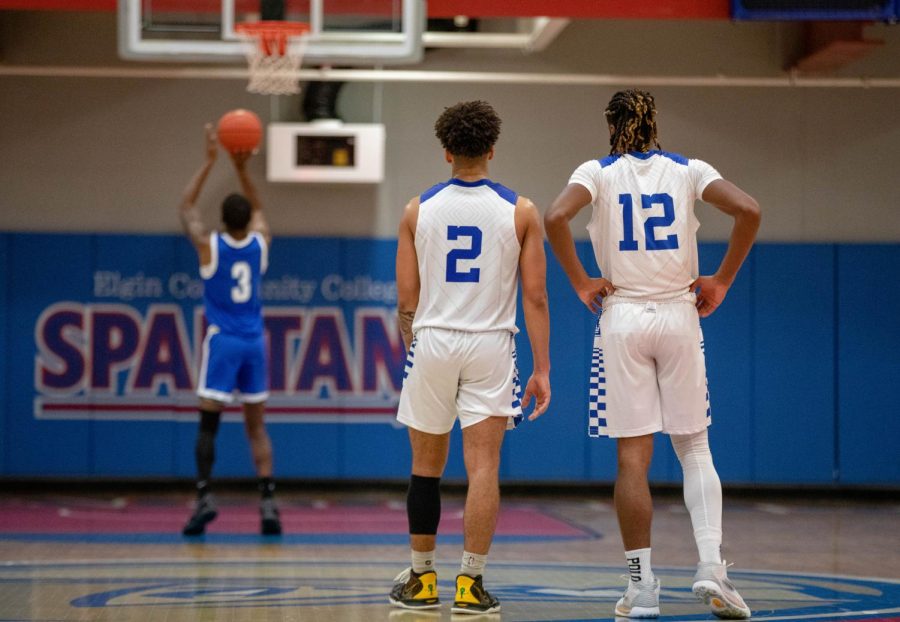Guard Jordan Wilkins, number 2, and guard Dorien Little, number 12, watch as a player from William Rainey Harper College shoots a free throw on Dec. 3. 