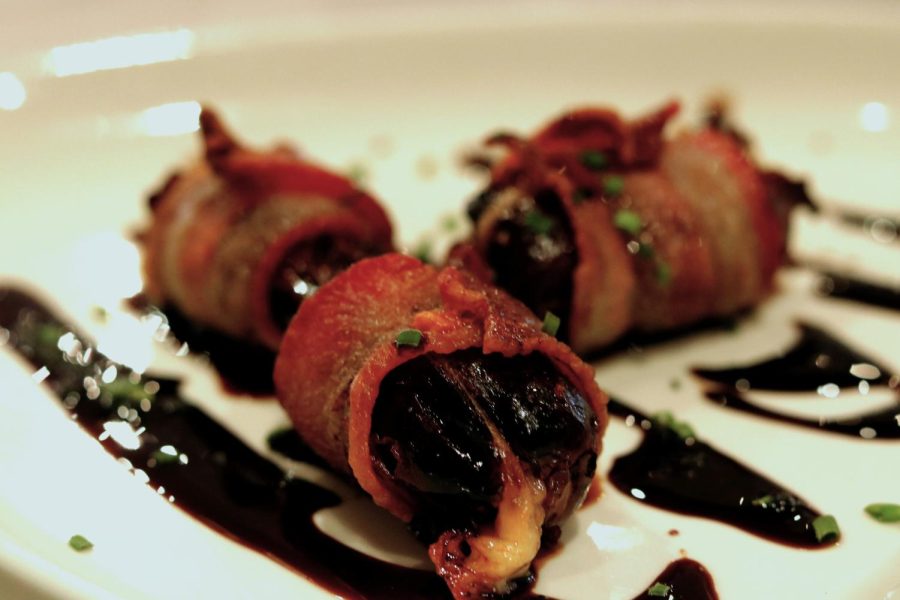 Gluten-free bacon wrapped dates stuffed with Manchego cheese and drizzled with balsamic glaze.