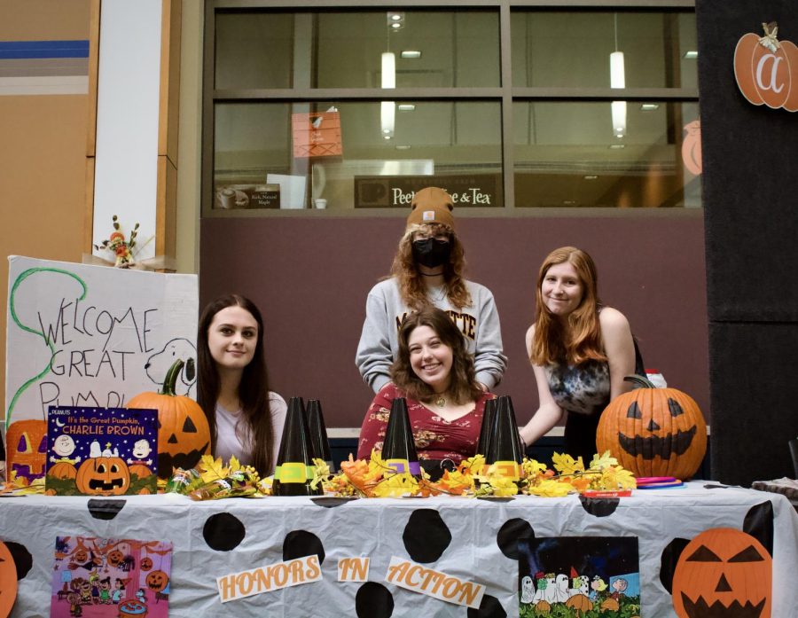 ECC students Emily Mostaccio, left, Ely Thompson, front, Michelle Gembala, right, and Sfo Foley pose at the Honors in Action table at Fall Fest on Oct. 5, 2022. 