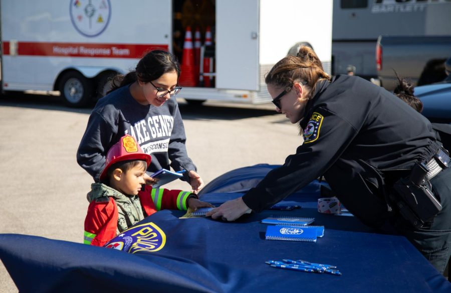 Community Engagement Officer Kara Burroughs, right, of the Carpentersville Police Department hands a notebook to Liam Aburtl, 3, at the ECC Center for Emergency Services Open-House Event in Burlington on Saturday, Oct. 15, 2022. 