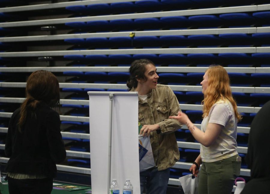 April Weirich (left) and Abby Swanson joke around while speaking with a representative from Binghamton University at College Night in Building J on Wednesday, Oct. 12, 2022. 