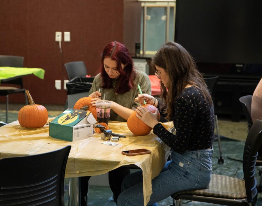 ECC students Piper Tunnely, left, and Stella St. Clair stencil out their carving lines at Fall Fest on Oct. 5, 2022. 