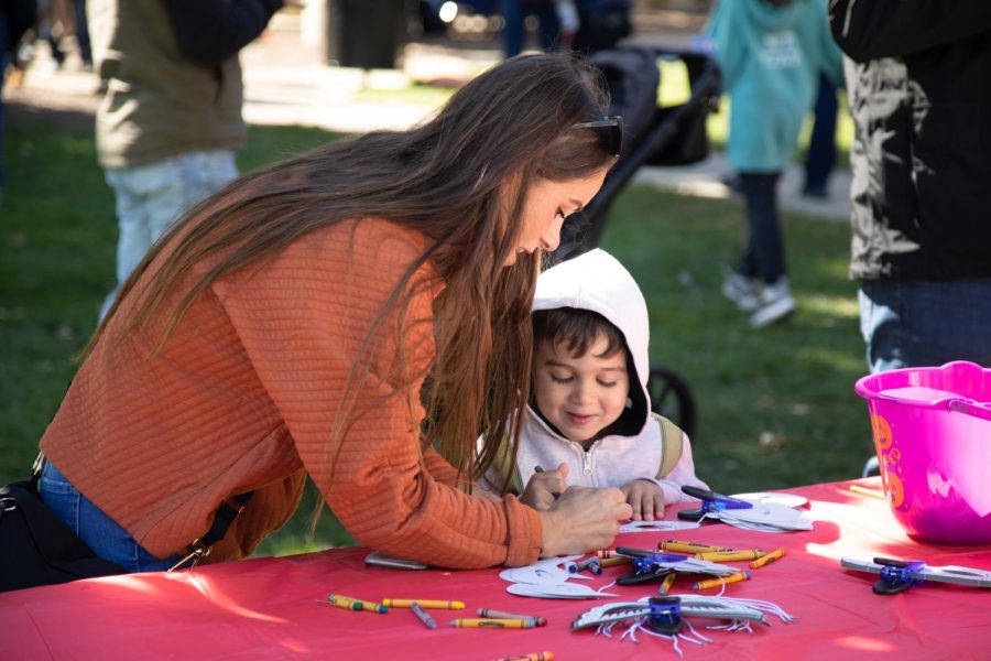 Stephanie, left, and Morrison (3) Rekas of Lake in the Hills color a paper mask at the J & R Herra Home Services tent in St. Charles Lincoln Park during Scarecrow Weekend on Oct. 8, 2022. 