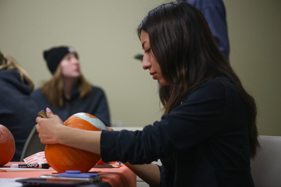 First-year-student Giselle Miranda closely paints her pumpkin at the Pumpkin Painting Party in Building B on Oct. 20, 2022.