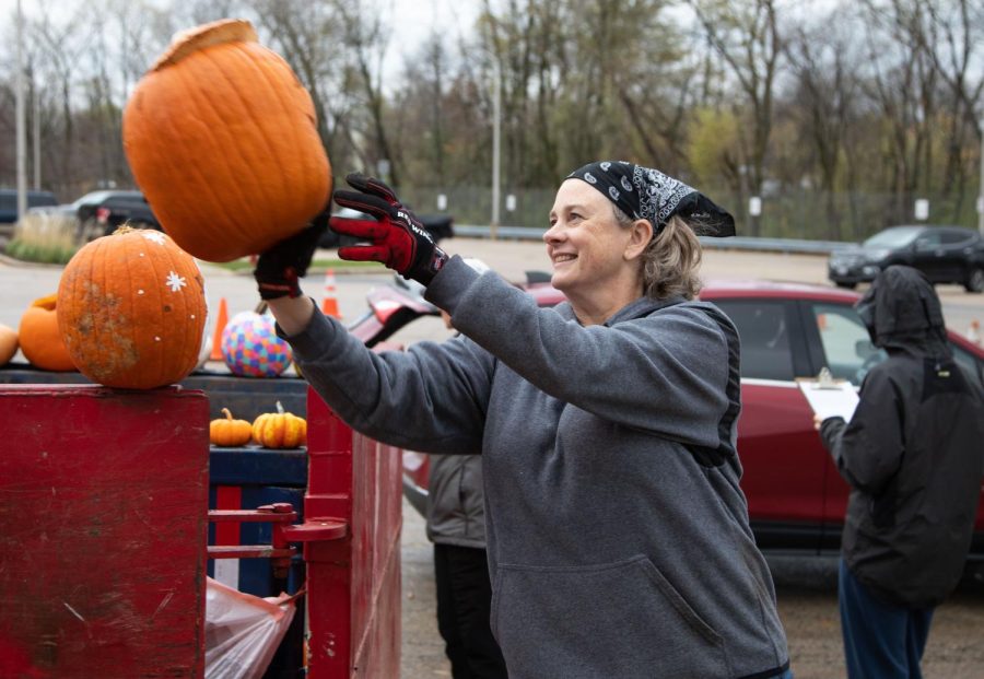 Volunteer Megan Bockenhauer of St. Charles throws a pumpkin into a dumpster during the Green Your Halloween pumpkin composting event at the St. Charles Public Works Facility in St. Charles on Saturday Nov. 5, 2022.  