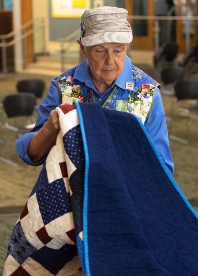 Quilts of Valor volunteer, Shirley Pflederer folds a quilt during the Veterans Day Celebration in the Jobe Lounge at ECC on Friday Nov. 11, 2022. The Quilts of Valor is an organization that presents veterans with a hand-made quilt. 