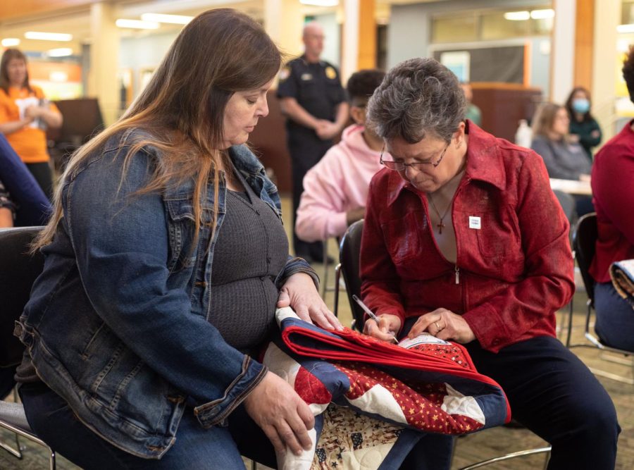 Quilts of Valor volunteer, Patty Harrer, right, writes on the label of a quilt presented to veteran Ruth Ann Schatz during the Veterans Day Celebration in the Jobe Lounge at ECC on Friday Nov. 11, 2022.  