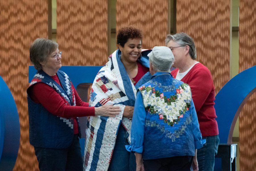 Honoree and second-year student Tyra Benson, middle, receives her Quilt of Valor from Naomi Payne, left, Shirley Pflederer, front, and Carol Earsley during the Veterans Day Celebration in the Jobe Lounge on Friday, Nov. 11, 2022. 