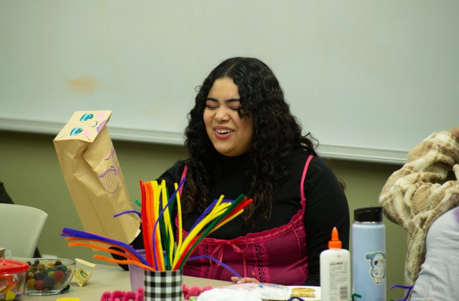 Third-year-student Salma Armenta laughs while playing with the paper bag puppet she made at the Sell Your Art Now meeting hosted by the Art and Design club on Nov. 15, 2022. 