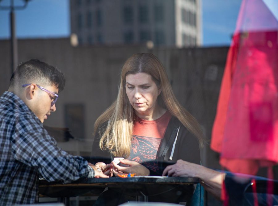 Melissa Routzahn, right, closely watches Lagunes as he demonstrates specific folds at Side Street Studio Art in Downtown Elgin on Nov. 6, 2022.