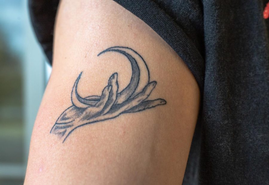 ECC student Ryan Kemble shows off his tattoo design with a crescent moon in an outreached hand. To him, the tattoo symbolizes the brotherhood and connection he has with his brother. The two both got matching tattoos: his brother got the sun and Kemble got the moon.