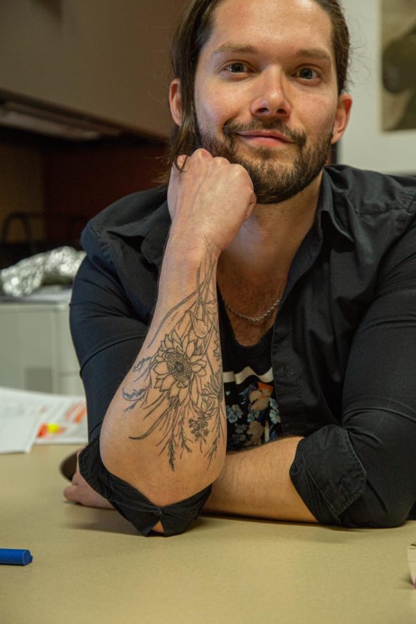 Professor of English and LGBT Literature Kellen Bolt shows off his floral tattoo on Feb. 21, 2023. Bolt, who grew up in Kansas and eventually moved to California for a short span, commemorated his home region by getting flowers representative of Kansas and Illinois tattooed on his outer forearm.