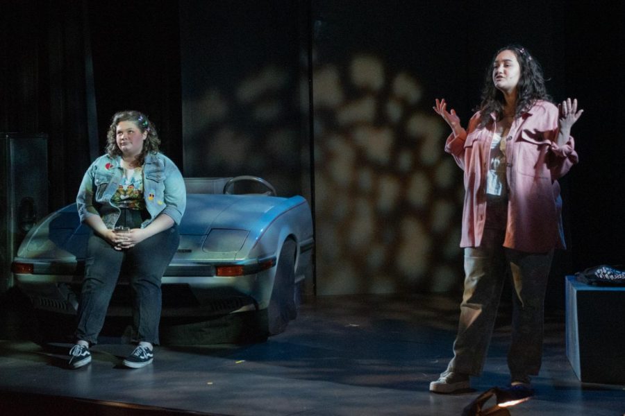 Kelly (left), played by Olivia Litton, leans against a vintage car as Sam, played by Gabrielle Urbina, speaks in the Spartan Auditorium on Feb. 23, 2023. 