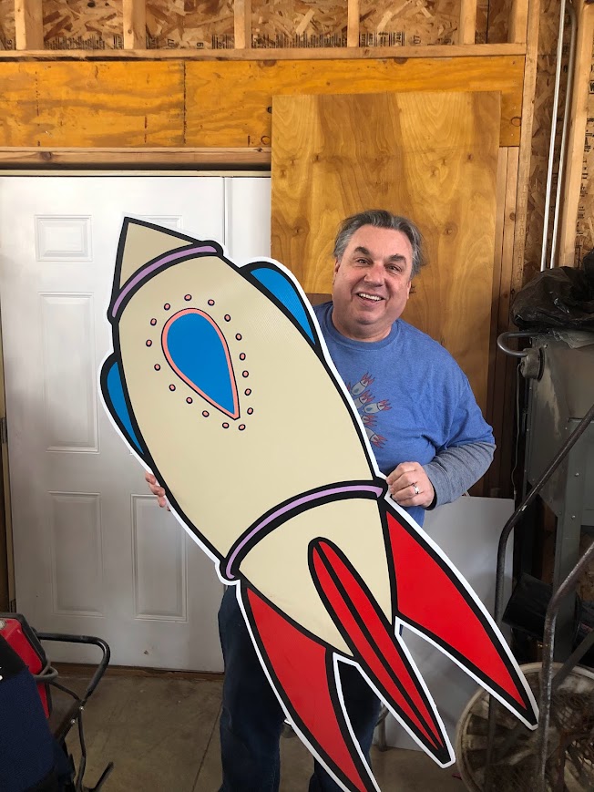 Howard Russo holding one of his rocket ship designs at his workshop. 