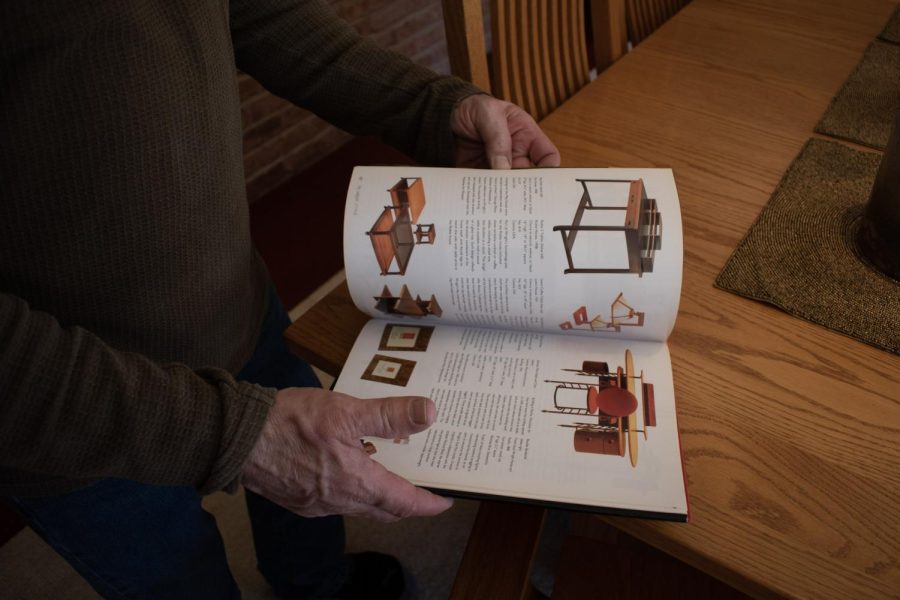 Mike Petersdorf flips through a book highlighting works by Frank Lloyd Wright in Hampshire, IL on April 6, 2023. The bottom right desk  and chair is located in the Johnson Wax Administrative Building in Racine, WI.