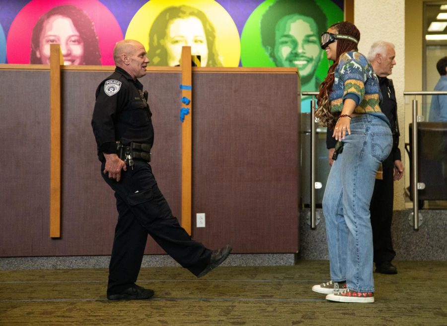 ECC Police Officer John Sumter shows Second-year student Zsu Zsu Mack the difficulty of walking a straight line while she wears goggles that simulate vision while drunk at the Drunk Busters Event in the Jobe Lounge on Thursday, April 20, 2023.