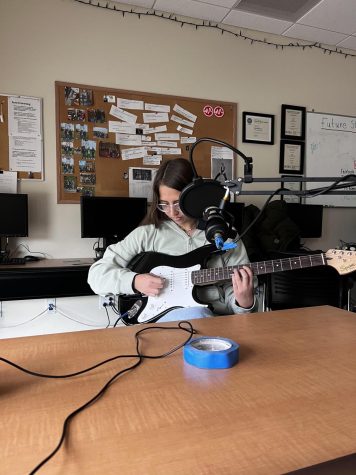 Observer staff writer Jenna Mckee plays her guitar on the Eye of the Observer podcast. 
