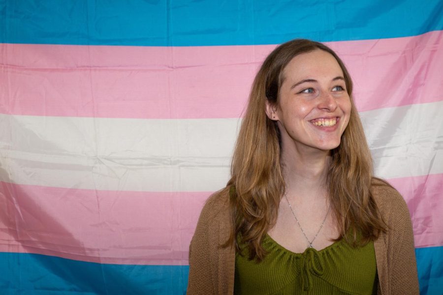 ECC student Jennifer McDonnell smiles in front of the transgender flag on May 3, 2023.