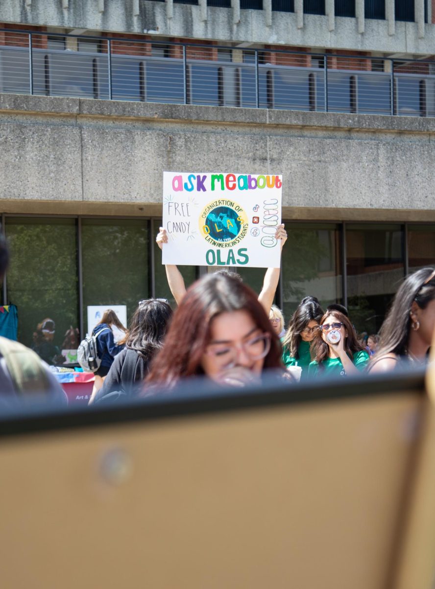 A member from the Organization of Latin American Students (OLAS) holds up a sign to promote the club during Clubchella on Aug. 30, 2023. 