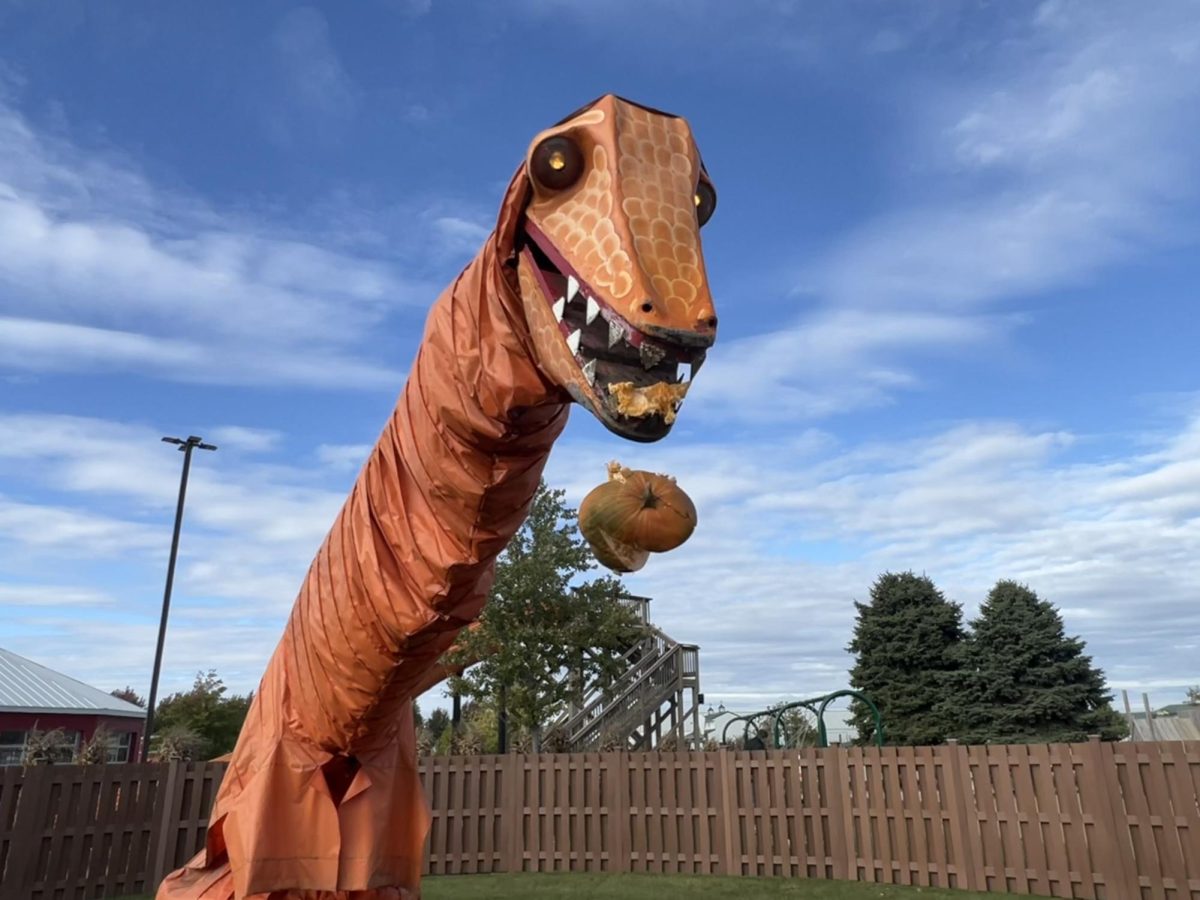A chewed-up pumpkin falls from the mouth of the pumpkin-eating dinosaur at Goebberts Farm in Pingree Grove, IL on Oct. 10, 2023.