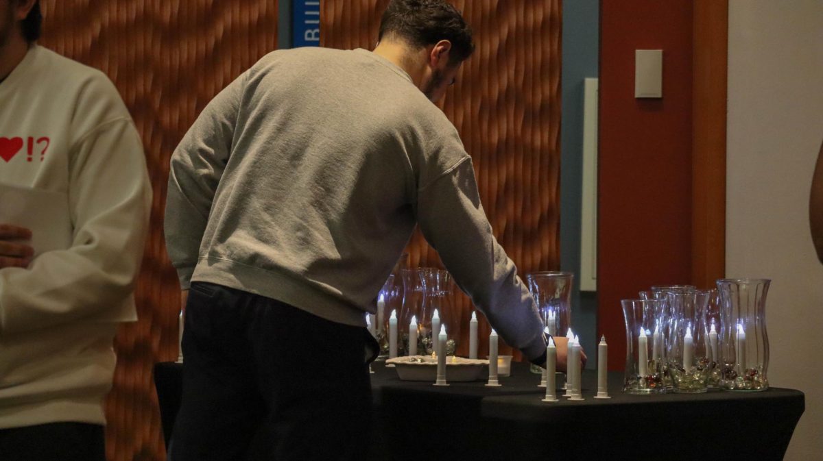 An ECC student placing a candle on the Palestine vigil in Jobe lounge at the Candlelight Vigil for Palestine event in the Jobe Lounge on Nov. 29, 2023.