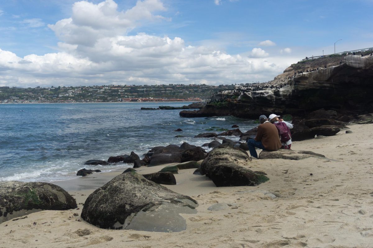 A couple sits on a rock at La Jolla Beach in San Diego, California on Mar. 6, 2024. 