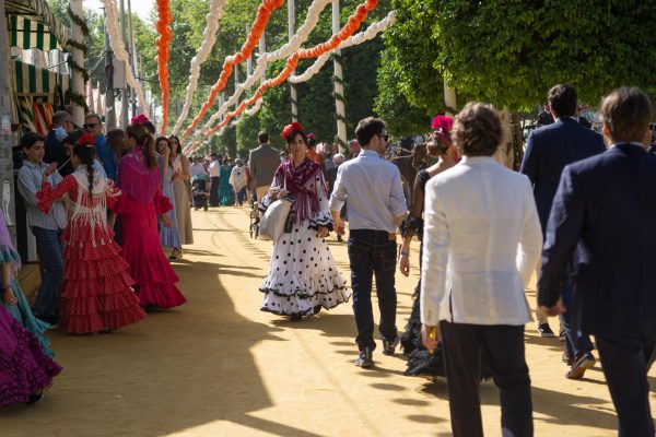 Attendees walk along las casetas at la Feria de Abril en Seville, Spain.