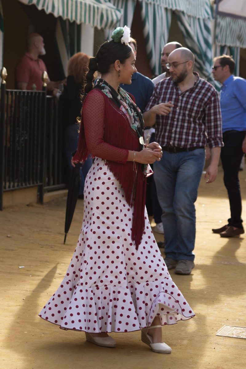 A typical traje de flamenca or gitana will feature an up-do with a large front-facing flower, an embroidered shawl called a mantón and a voluminous, flared skirt. 
Accessories are highly encouraged and espadrille-style heels are very common. Overall, the trends continue to change year-by-year. 
