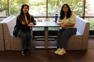 Two students wearing tennis shoes sitting across from each other at a table.