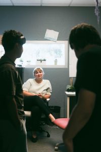 Melanie Schaefer talks with students as they stand by her office door.