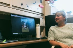 Melanie Schaefer looks enthusiastically at a photo of a soccer player in game, on her computer.