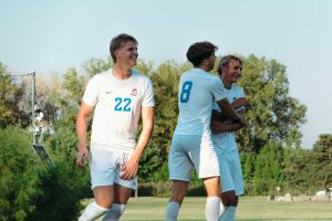 Nick Prus smiles as he's embraced by his teammates after scoring a goal.