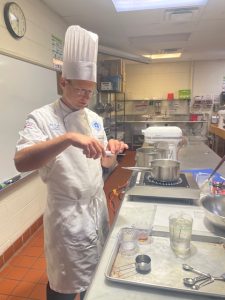 Prof. Guzzaldo holding a candy thermometer in the kitchen.