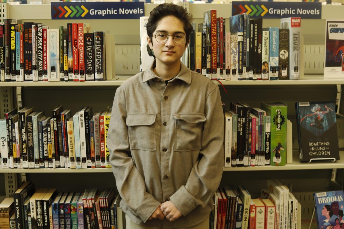 Student standing in front of shelves of books.