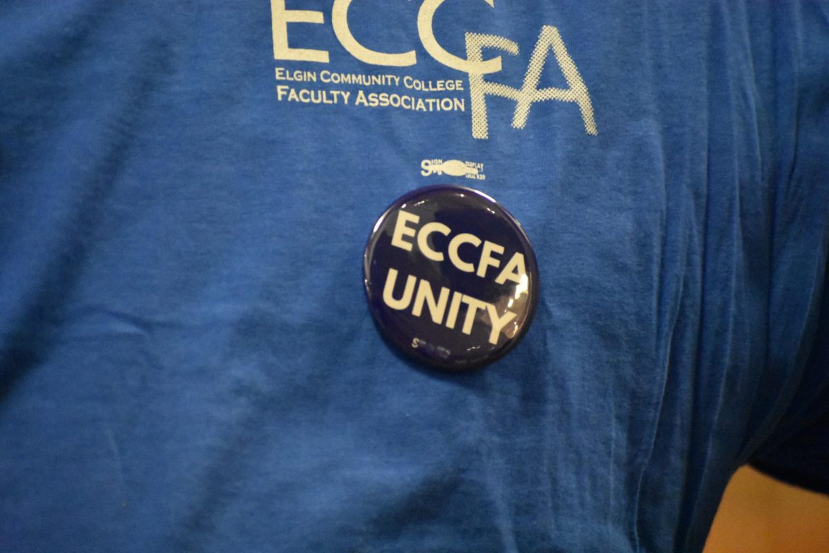 The ECCFA logo on a blue t-shirt and button, worn by a faculty member.