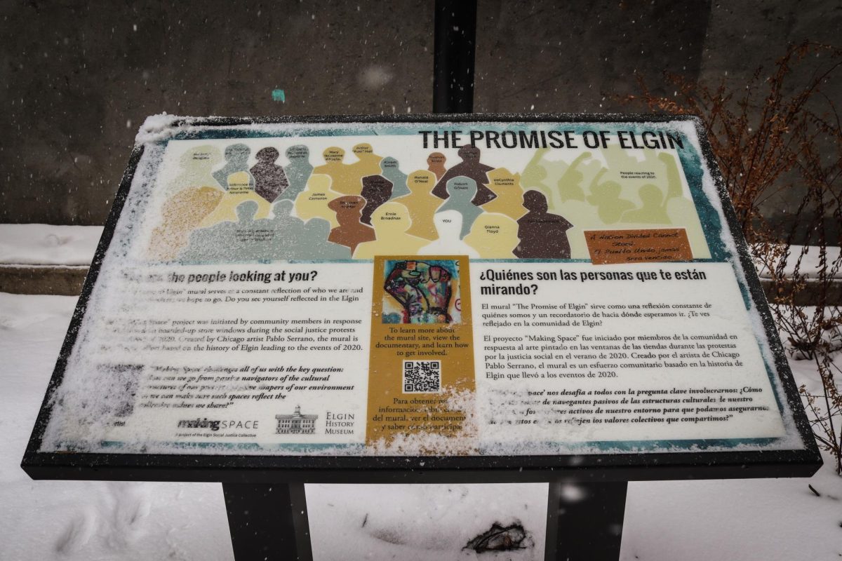 The informational sign places in front of The Promise of Elgin Mural, on Jan. 30, 2026. The sign tells readers who the figures on the mural are, and the same information is translated in Spanish on the right side.