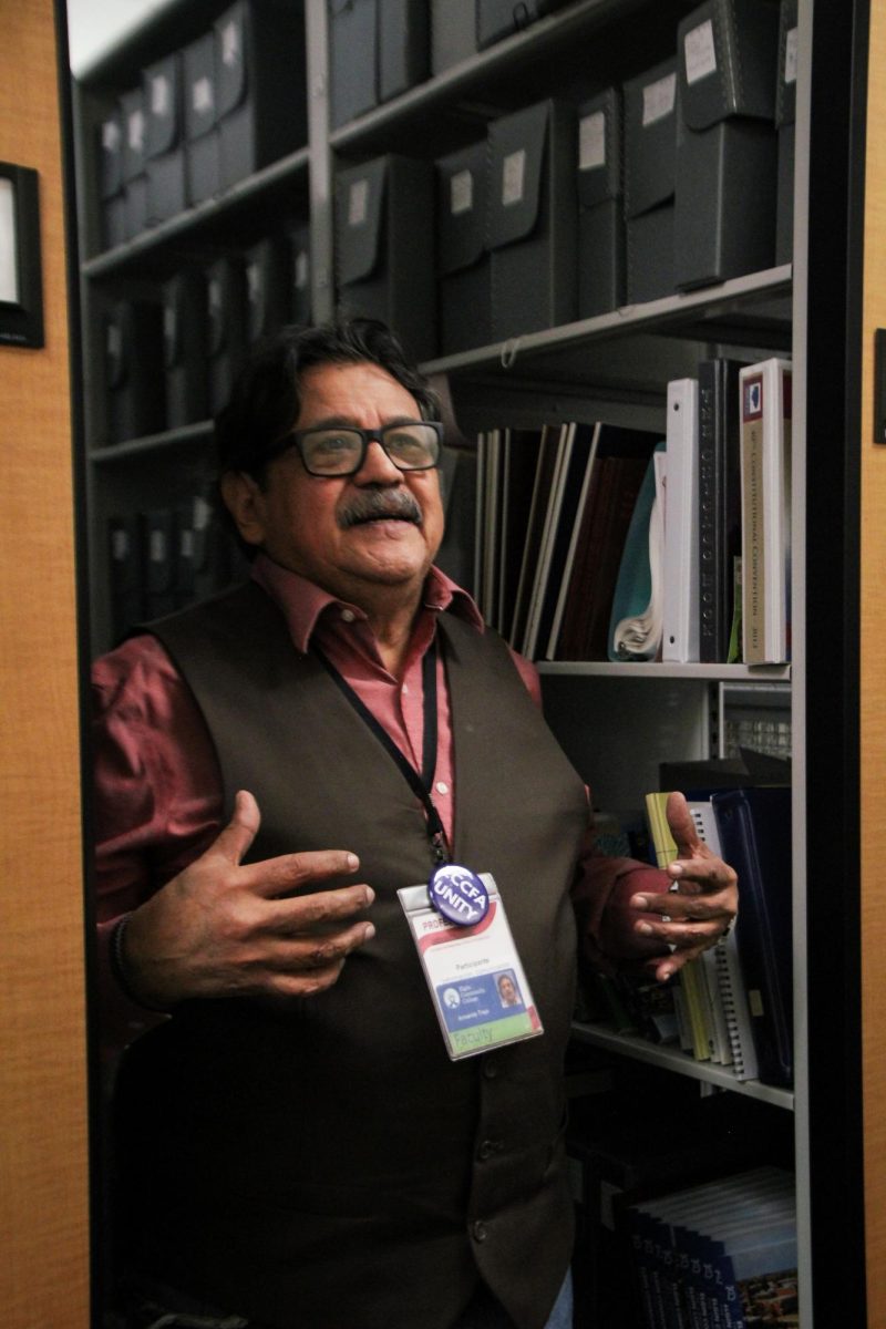 Armando Trejo talking while standing in-between storage shelves in the Archive Room.