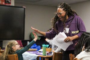 Dr. Brittany Barber and a young girl high-five in the school library during the after-school Girls in Motion program.