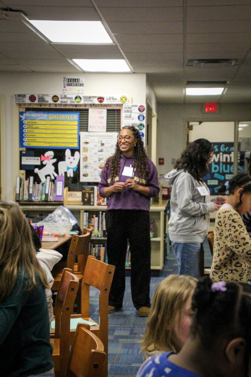 Dr. Brittany Barber stands smiling as she surveys the seated children taking part in the Girls in Motion program.