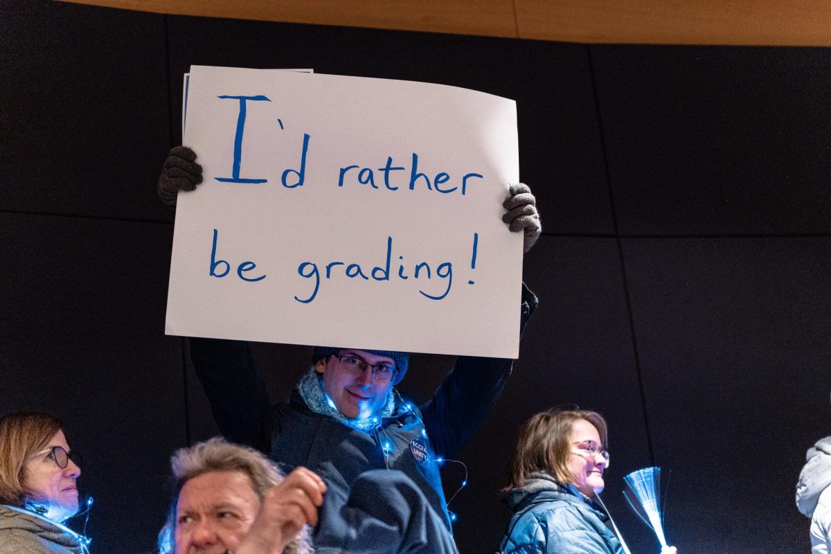 "I'd rather be grading!": Chris Cunningham holds a sign regarding the delay of a fair contract during a meeting on campus with trustees, on January 27, 2026. With bargaining continuing into the next semester, teachers have maintained to work within their previous contract with the college, not exceeding the duties and responsibilities stated in that contract.