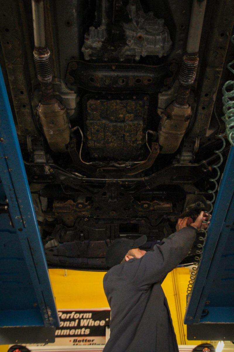 Victor Herrera, General Specialist, inspects the undercarriage of a car at Acorn Tire & Service on Feb. 10, 2026. Metal components of the undercarriage, like the exhaust, subframe, and suspension are affected by cold weather.