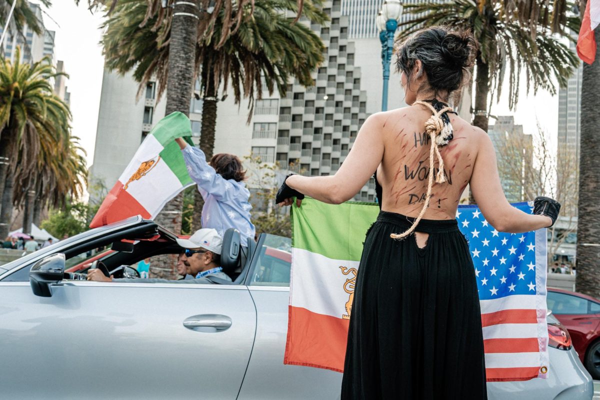 Iranian-American demonstrators wave "Lion and Sun" Iranian flags, along with United States flags, outside Embarcadero Plaza, San Francisco, on Mar. 7th, 2026. People participating in the event expressed support for the Trump administration's intervention in Iran, following the death of Supreme Leader of Iran, Ali Khamenei.