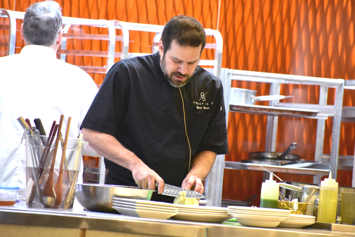 At the Spartan Terrace, ECC alumni Chef Eric Olson answers questions that the culinary students ask on Feb. 19, 2026. At the same time he worked on chopping an ingredient for a food dish.
