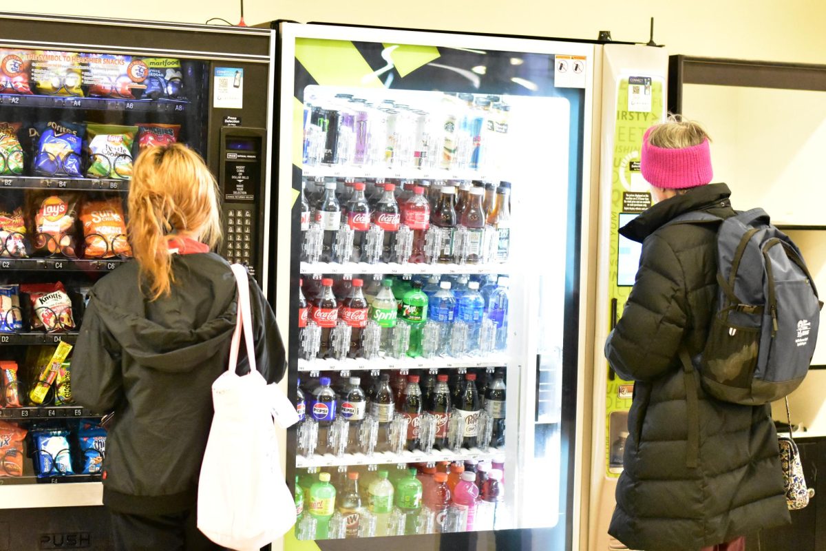 Two students using the vending machines in building B on Mar. 23, 2026. The vending machines were there to allow anybody to grab a quick snack while on campus.